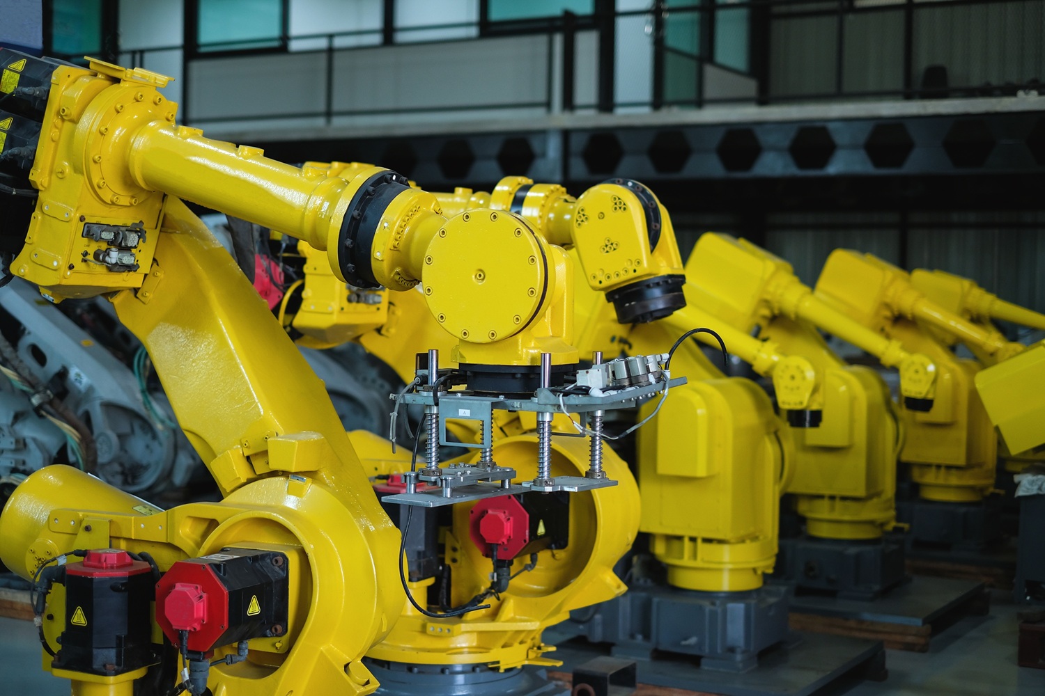 row of yellow automatic welding robot arms at automobile industrial factory.